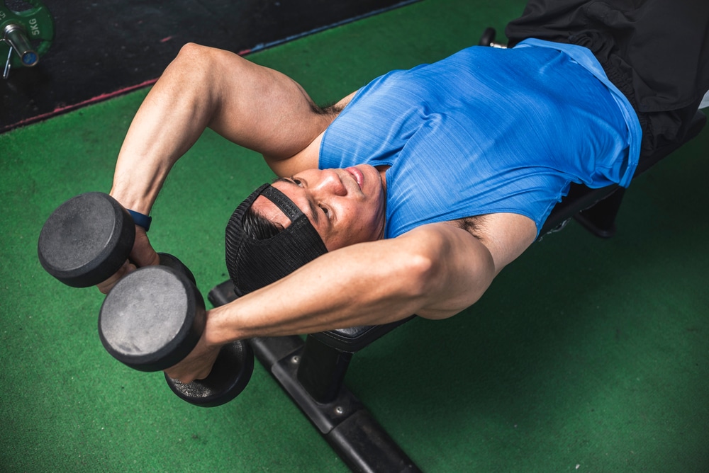 A Fit Asian Man Does A Set Of Lying Dumbbell