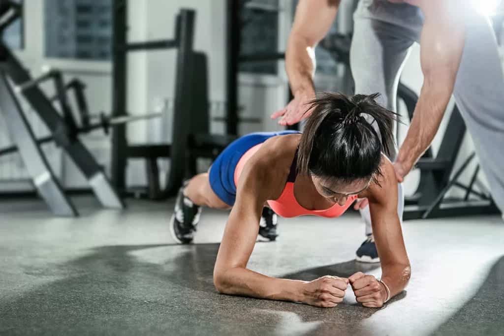a gym instructor giving core stability exercise guide to a women