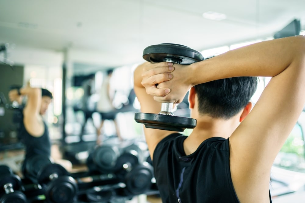 Active Asian Sportsman Doing A Weight Training Exercise By Lifting