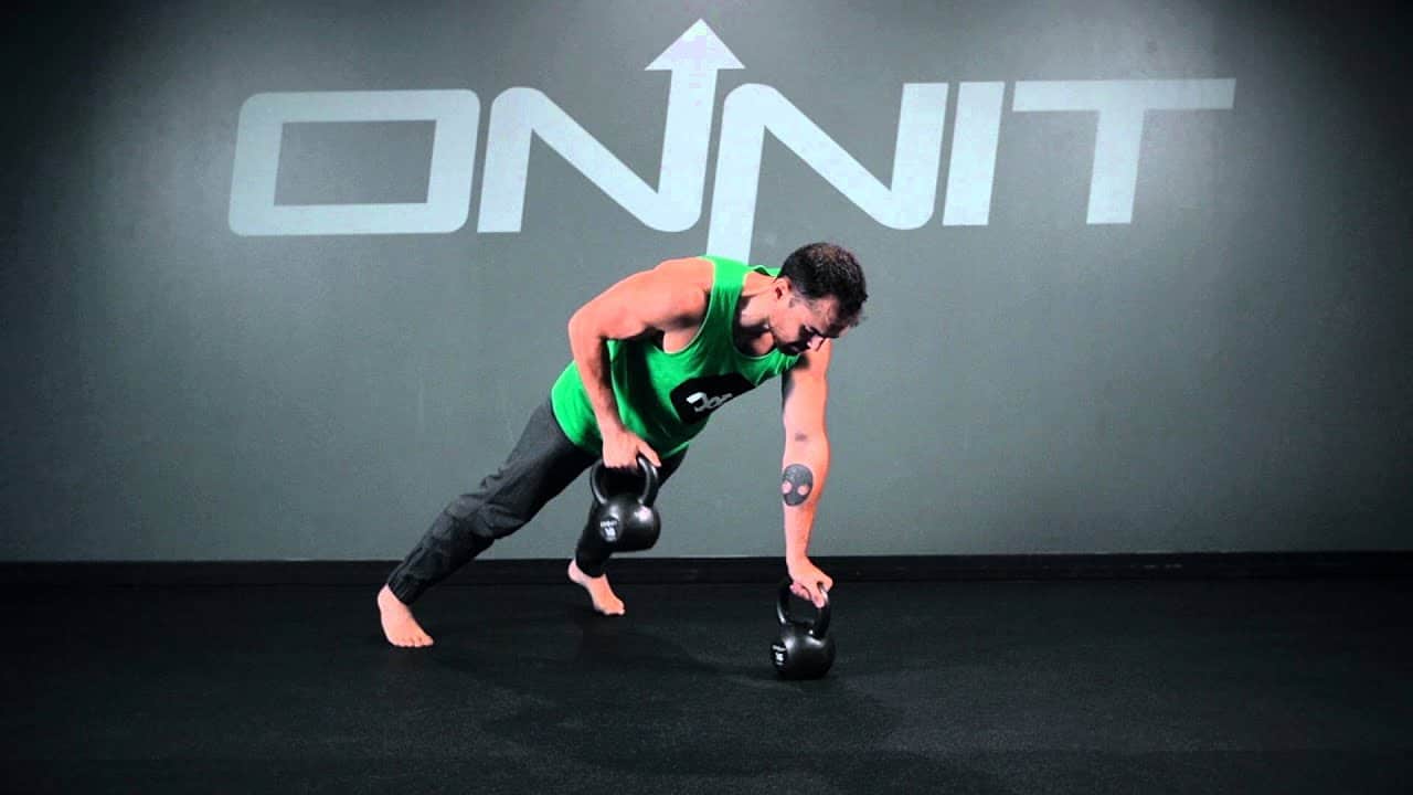 a man is doing kattle ball exercise with one hand on floor and one in air