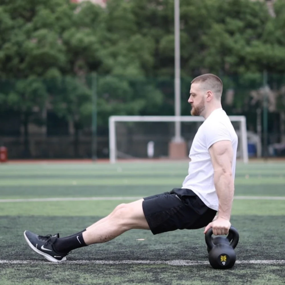 a person is doing Kettlebell Tricep Dips outside the gym