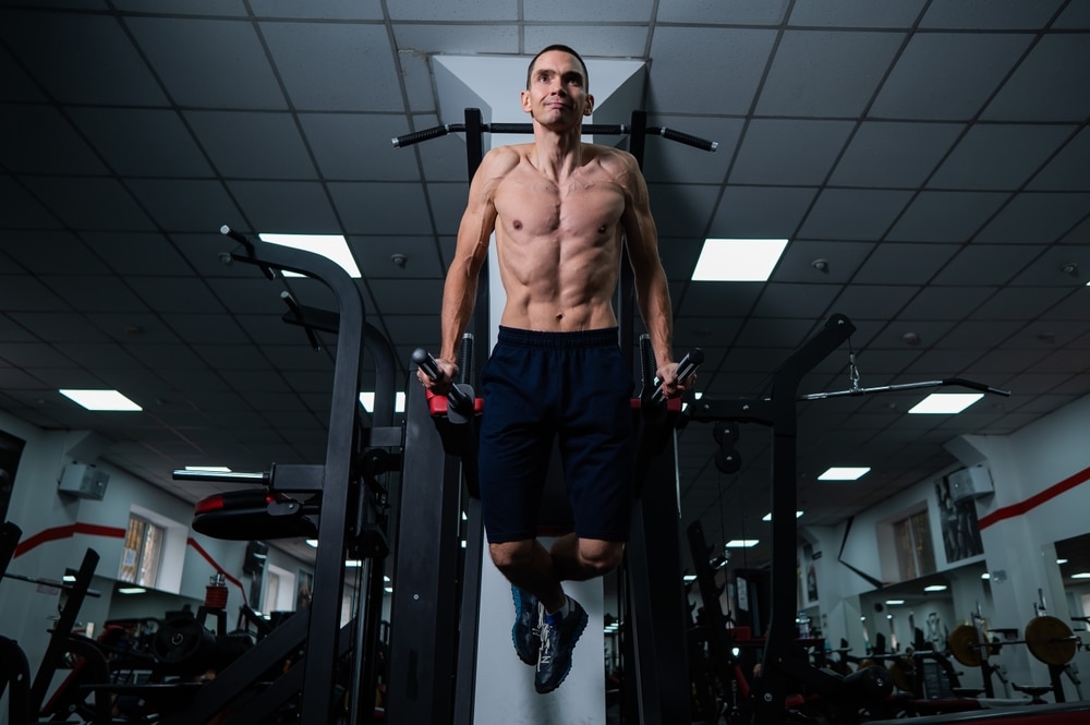 Shirtless Man Doing Triceps Dips From Parallel Bars In Gym