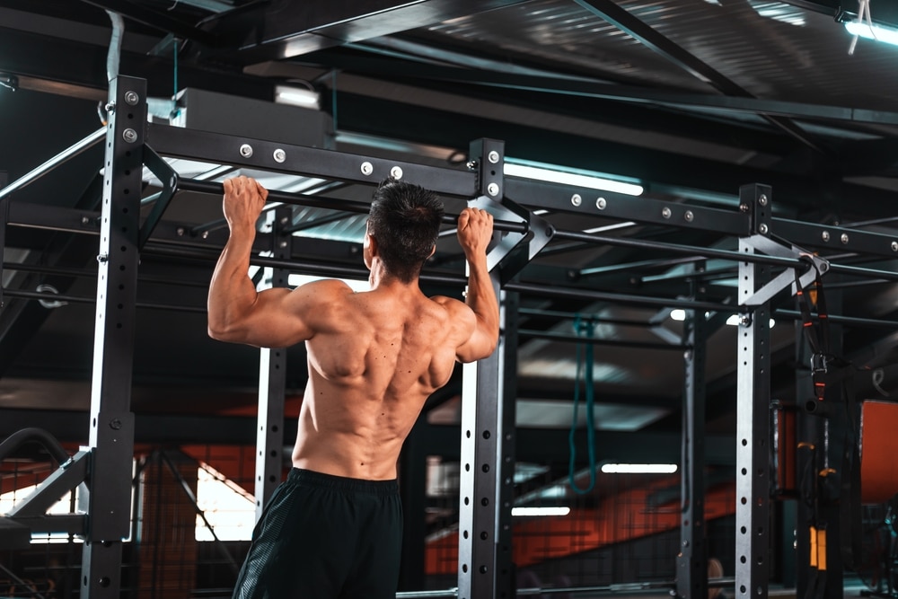 Back View Of Muscular Sportsman Doing Pull Ups On Horizontal